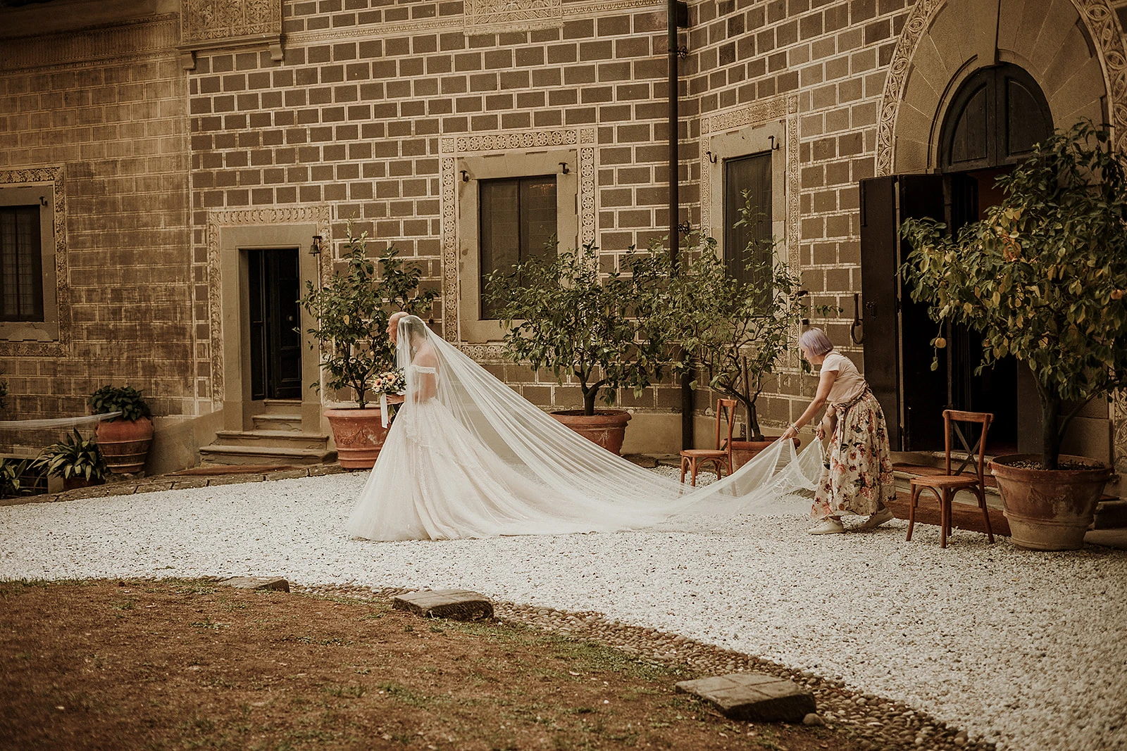 Ilaria, wedding helper di Euphoria Events, coordina l'ingresso della sposa e le sistema il velo durante il matrimonio in toscana