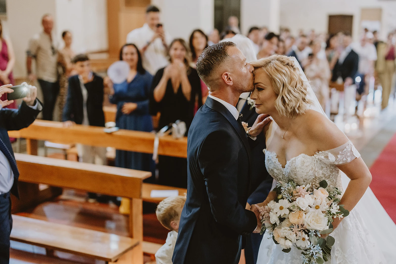 lo sposo bacia sulla fronte la sposa all'ingresso della cerimonia di matrimonio in Mugello