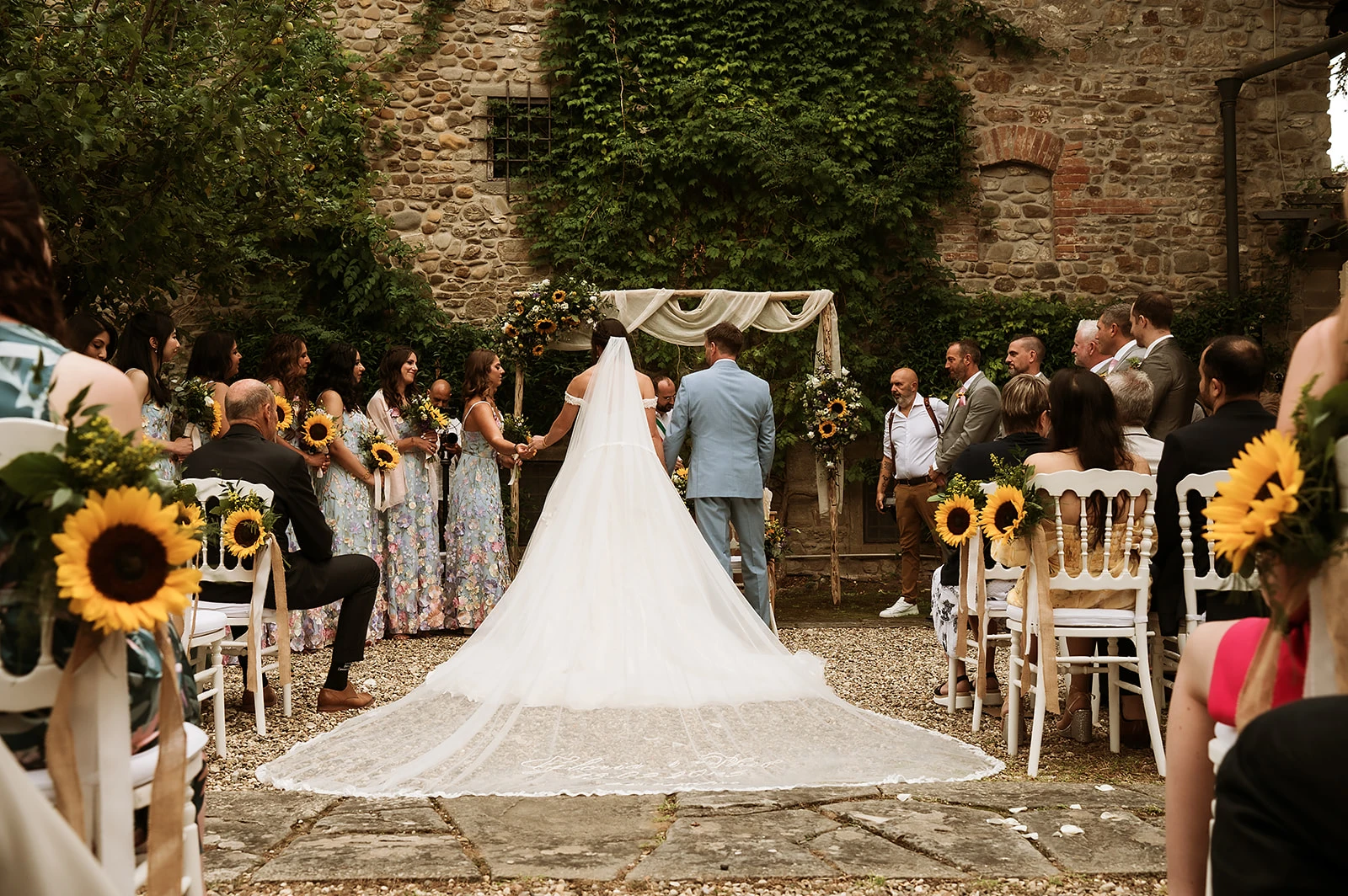 Momento del matrimonio di Phil e Gloria allestito con girasoli nel roseto del Castello di Barberino