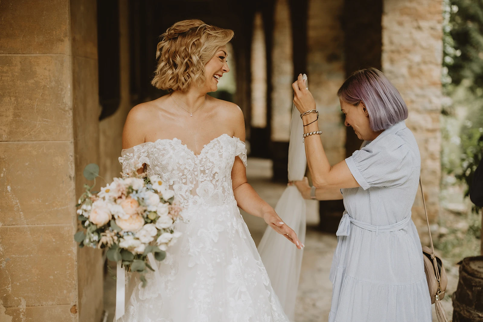 la sposa sorride a Ilaria la wedding helper di euphoria events che le prende il velo
