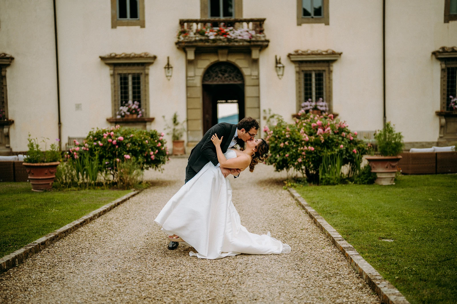 Foto memorabile degli sposi davanti all'ingresso della villa di matrimonio in toscana